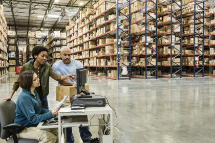 Warehouse workers checking inventory on a computer in a large distrubiton warehouse. Top 5 Major Inventory Management Techniques
